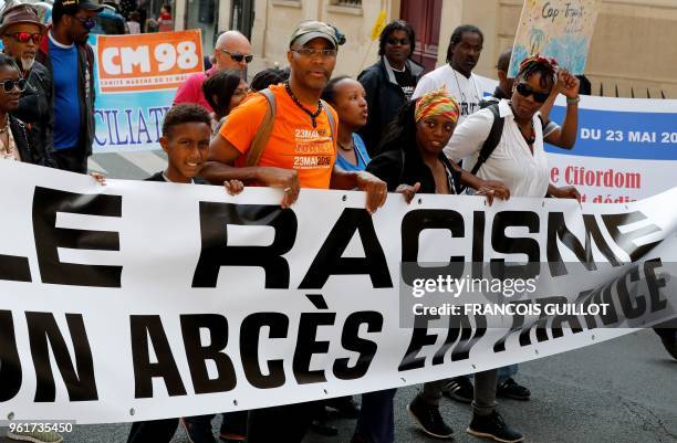 People hold a banner reading "Racism is an abscess in France" as they take part in a march in memory of victims of slavery on May 23 in Paris. - The...