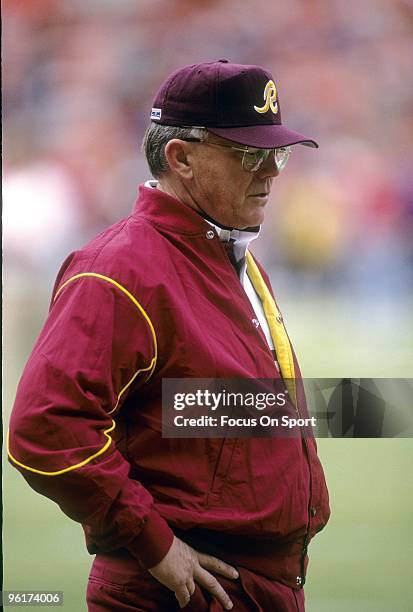 Joe Gibbs head coach of the Washington Redskins on the field watches his team warm-up before a mid circa 1980s NFL football game. Gibbs coached the...