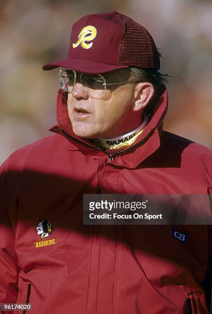 Joe Gibbs head coach of the Washington Redskins on the field watches his team warm-up before a mid circa 1980s NFL football game. Gibbs coached the...