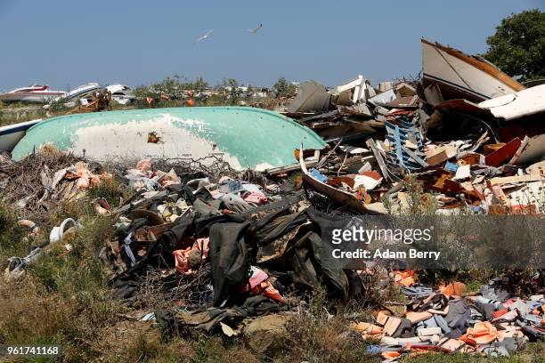 The remains of boats used by refugees in their attempted crossings from Turkey to Greece lay amongst thousands of used life preservers and pieces of...