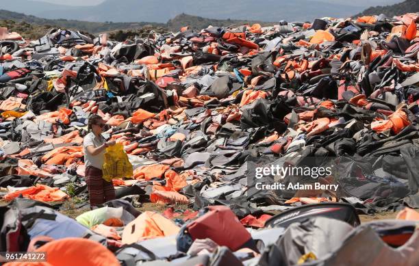 Thousands of used life preservers and pieces of rafts used by refugees in their attempted crossings from Turkey to Greece lay in a pile on the island...