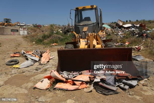 Bulldozer sits amidst piles of discarded life preservers used by refugees in their attempted crossings from Turkey to Greece on the island of Lesbos...