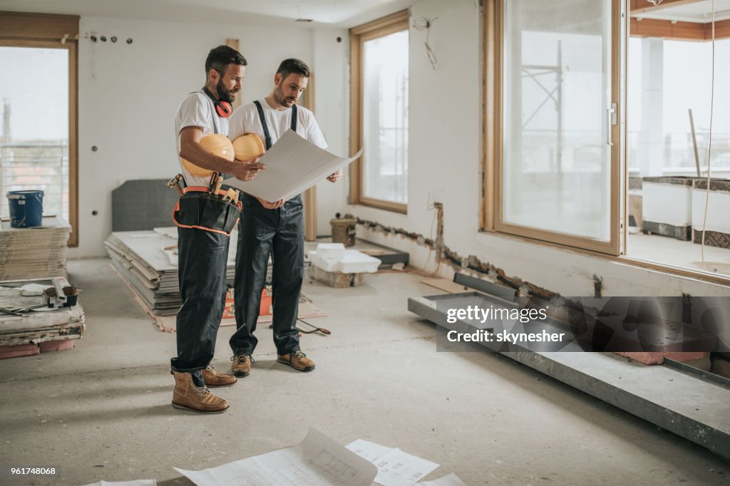Voller Länge von Bauarbeitern, die Baupläne in der Wohnung zu analysieren.