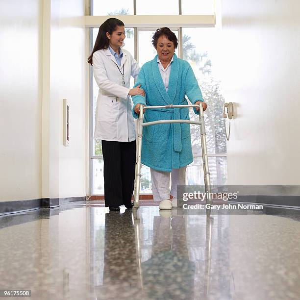 doctor helping patient walk in corridor - norman elder stock-fotos und bilder