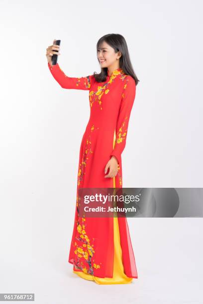 young woman wearing vietnamese red color ao dai, smiling, selfie, video call. - ao dai stockfoto's en -beelden