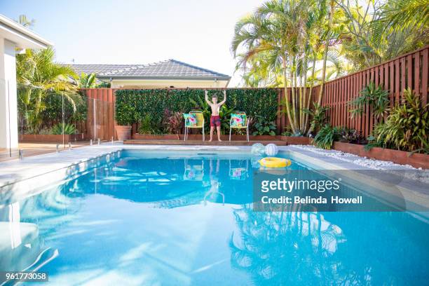 australian boy enjoys swimming and playing in backyard pool - kids pool games stock-fotos und bilder