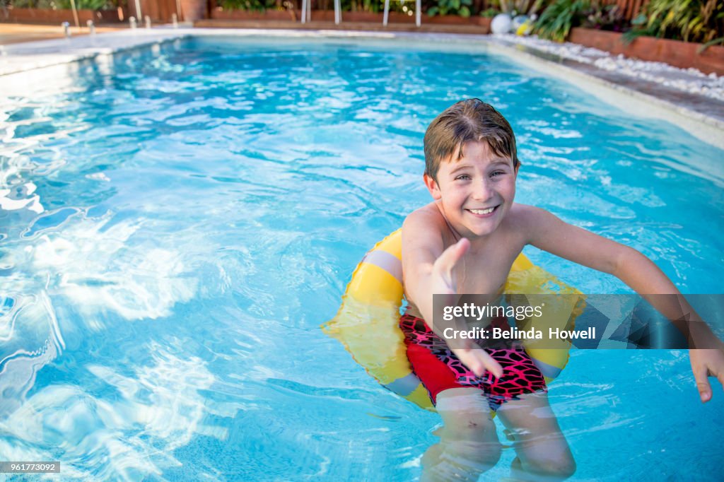 Australian boy enjoys swimming and playing in backyard pool