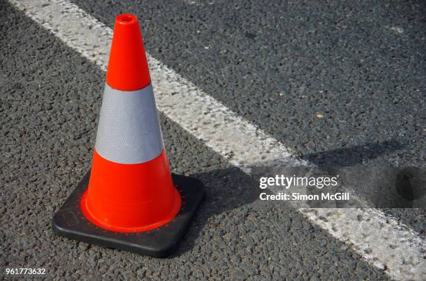 traffic cone next to the line marking on the shoulder of a road - safety cone stock pictures, royalty-free photos & images