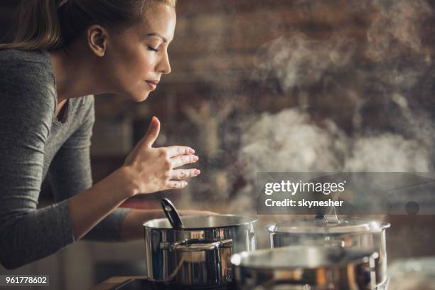 mooie vrouw met heerlijke lunch ruiken ze bereidt in de keuken. - trying stockfoto's en -beelden