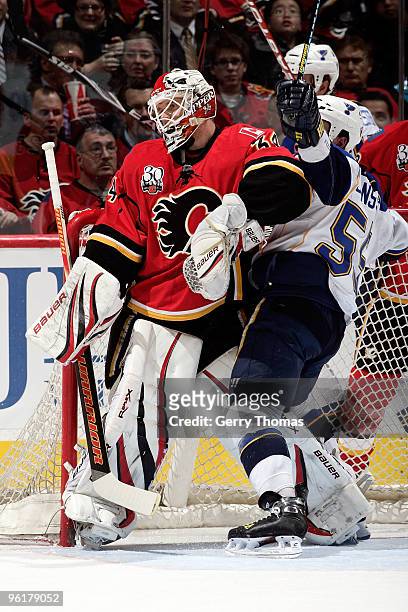 Miikka Kiprusoff of the Calgary Flames collides in the crease with Cam Janssen of the St. Louis Blues on January 25, 2010 at Pengrowth Saddledome in...
