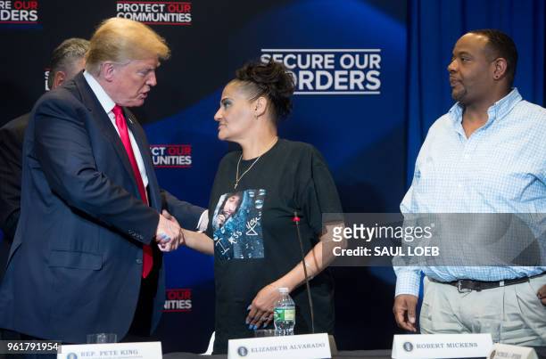 President Donald Trump shakes hands with Elizabeth Alvarado, alongside Robert Mickens, whose daughter was killed by MS-13 gang members, during a...