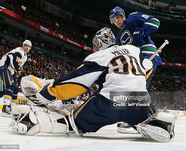 Steve Bernier of the Vancouver Canucks is stopped in close by Ryan Miller of the Buffalo Sabres as Henrik Tallinder looks on during their game at...