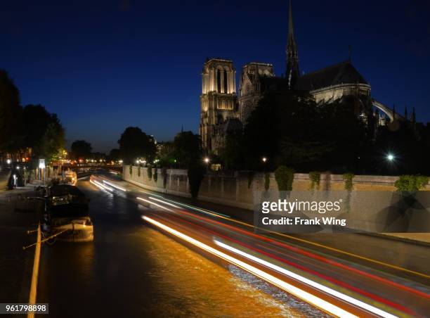 light streaks of boats cruising the seine near the notre dame in paris - bateau mouche stock pictures, royalty-free photos & images