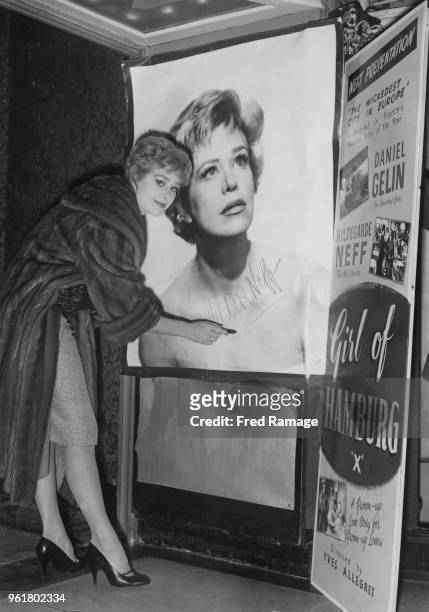 German actress Hildegard Knef autographs a large poster of herself at the Cameo Royal on Charing Cross Road, London, where her latest film 'La Fille...