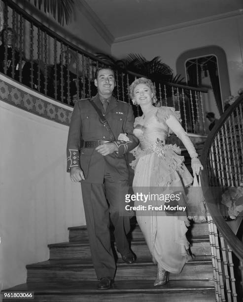 English actress Anna Neagle and actor Errol Flynn enter a reproduction of Romano's Restaurant on the Strand at the ABC studios in Elstree, UK, during...