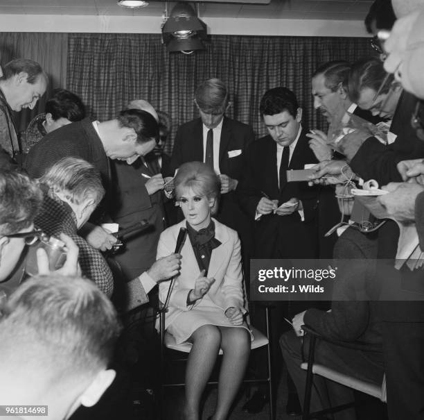 English singer Dusty Springfield is interviewed by the press at London Airport, after being deported from South Africa, 18th December 1964. She and...