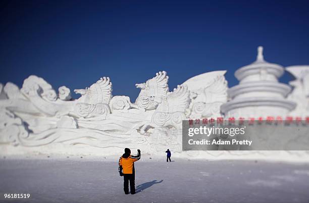 Visitors pose in front of a snow sculpture of the Temple of Heaven during the 26th Harbin International Ice and Snow Sculpture Festival on January...