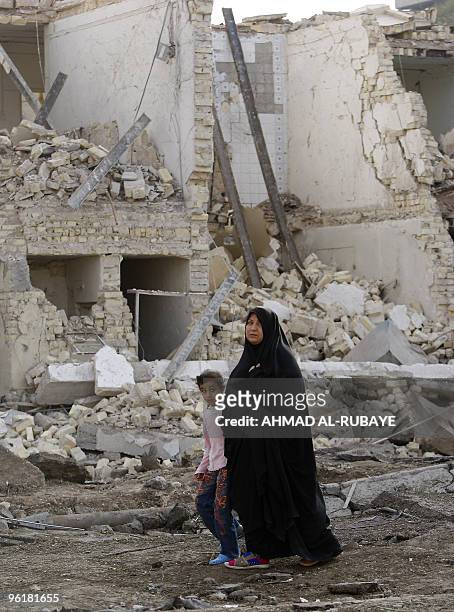 An Iraqi woman and a girl walk past destroyed houses a day after a bomb blast near the Hamra Hotel in Jadriyah, south of Baghdad, on January 26,...