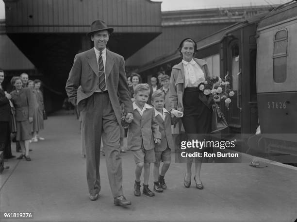 American actor James Stewart arrives at Waterloo Station in London with his wife, actress and model Gloria Hatrick McLean and her sons Ronald and...