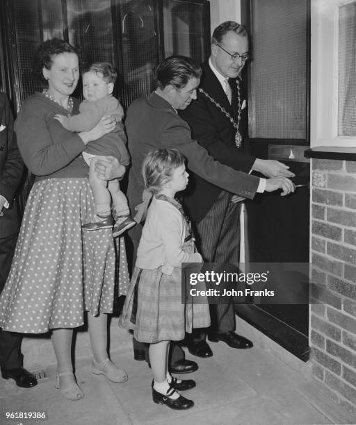 Councillor Patrick Stirling, the Mayor of Westminster, helps Mr and Mrs Donovan and their children Judy and Anthony take possession of Flat No. 1,...