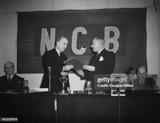 Manny Shinwell , the Minister of Fuel and Power, hands over a bound copy of the coal industry Nationalisation Act to Lord Hyndley , chairman of the...