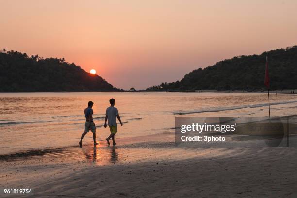 two men walking along the sunset beach - surf life saving stockfoto's en -beelden