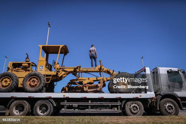 Truck driver stands on a Caterpillar Inc. Motor grader while parked on BR 040 highway during a protest against rising fuel prices in Luziania,...