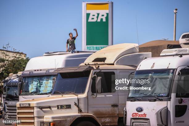 Driver takes a photograph of trucks parked at a Petroleo Brasileiro SA gas station near on BR 040 highway during a protest against rising fuel prices...