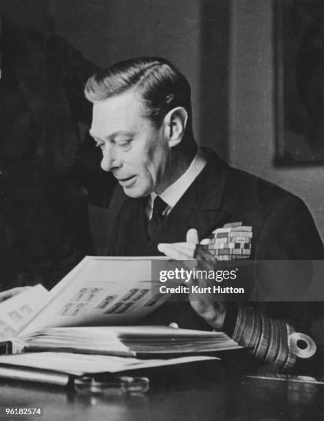 George VI, , King of Great Britain, peruses his stamp collection, December 1944. Original publication: Picture Post - 1860 - The King And His Stamps...