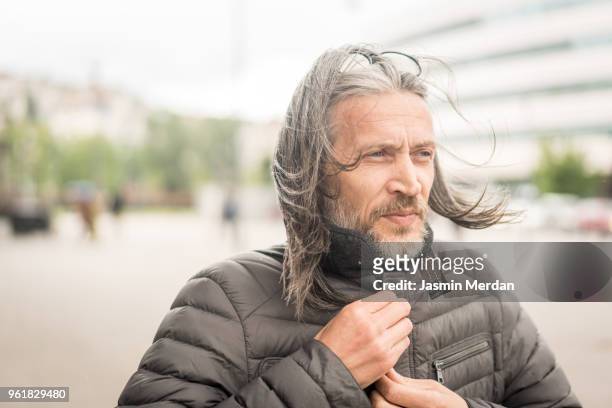 man with long hair on city street - urban air vehicle stock pictures, royalty-free photos & images