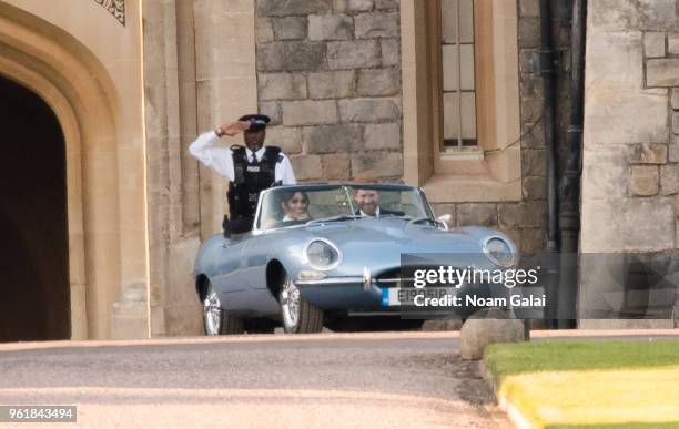 Prince Harry, Duke of Sussex, and Meghan Markle, Duchess of Sussex, leave Windsor Castle in Windsor on May 19, 2018 in an E-Type Jaguar after their...