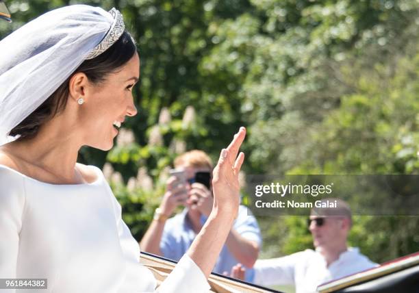 Meghan Markle, Duchess of Sussex waves from the Ascot Landau carriage during the procession after getting married to Prince Harry at St George's...