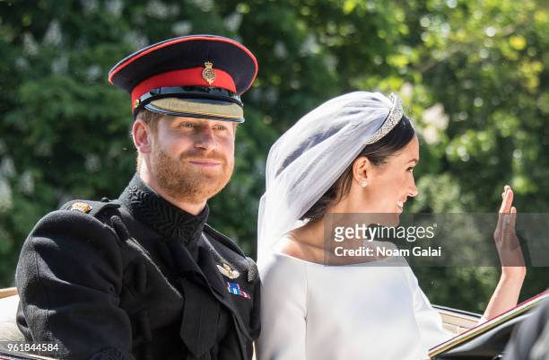 Prince Harry, Duke of Sussex and Meghan, Duchess of Sussex wave from the Ascot Landau carriage during the procession after getting married at St...