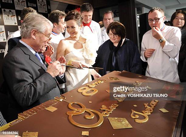 French chocolatiers cut a large chocolate cake, called opera, made by Dalloyau to serve to the guests at the opening ceremony of the Salon du...