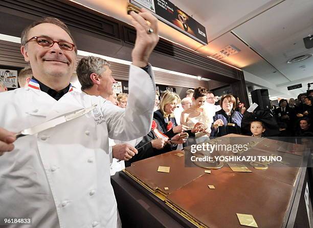 French chocolatier Jean-Paul Hevan cuts a large chocolate cake, called opera, made by Dalloyau to serve to guests at the opening ceremony of the...