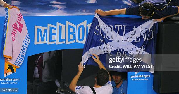 British tennis player Andy Murray signs a Saltire- Saint Andrews Cross - held by a supporter as he leaves the court following his men's singles...