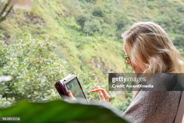 woman uses tablet computer in jungle environment - wonderlust computer stock pictures, royalty-free photos & images