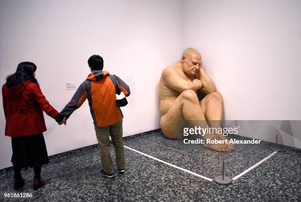 Couple visiting the Hirshhorn Museum and Sculpture Garden in Washington, D.C., look at a realistic polyester resin on fiberglass sculpture by...