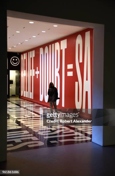 Museum visitor studies an art installation by Barbara Kruger which includes words and phrases printed on the floor and walls at the Hirshhorn Museum...