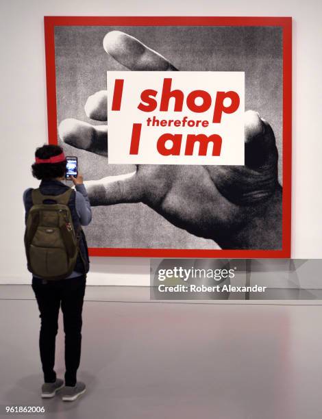 Museum visitor photographs a photographic silkscreen print by Barbara Kruger titled 'I Shop Therefore I Am' at the Hirshhorn Museum and Sculpture...