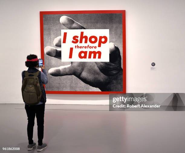 Museum visitor photographs a photographic silkscreen print by Barbara Kruger titled 'I Shop Therefore I Am' at the Hirshhorn Museum and Sculpture...