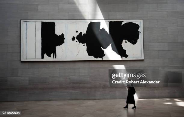 Museum visitor walks past a painting by Robert Motherwell, titled 'Reconciliation Elegy', as a beam of sunlight strikes the wall at the National...