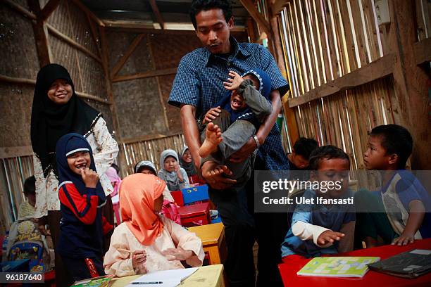 Teacher comforts a crying pupil at the temporary school in the Bantar Gebang landfill site, one of Jakarta's biggest dump sites, on January 26, 2010...