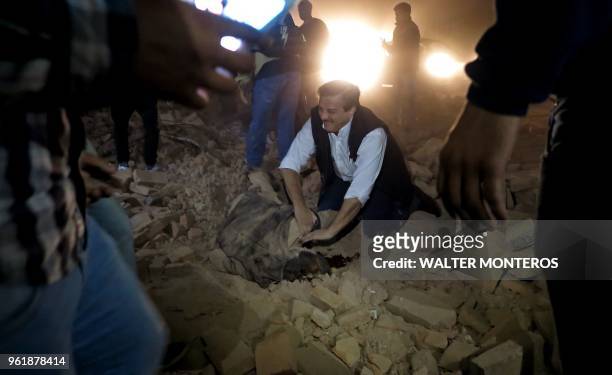 Man attempts to help a victim in the rubble minutes after the collapse of the old Parravicini movie theater building, in Tucuman, Argentina on May...