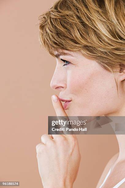 portrait of a woman with finger on lips, side view - woman with finger on lips stock pictures, royalty-free photos & images