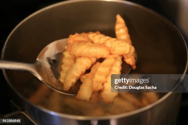 serving spoon in cooking oil with french fried potatoes - neue kartoffel gekocht stock-fotos und bilder