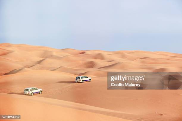 jeeps driving through the sand dunes in the desert near dubai. united arab emirates - rallyewagen stock-fotos und bilder