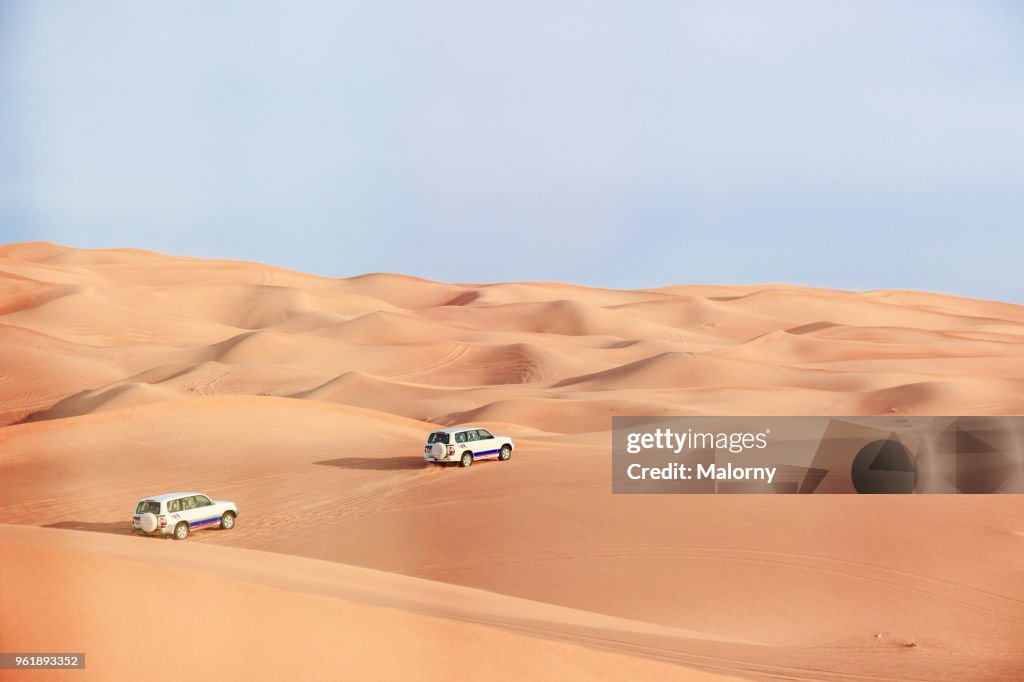 Jeeps driving through the sand dunes in the desert near Dubai. United Arab Emirates