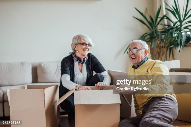 senior couple unpacking cardboard boxes - new sofa stock pictures, royalty-free photos & images
