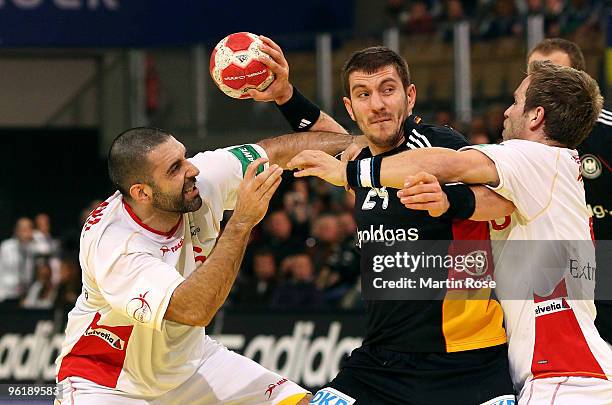 Michael Haass of Germany is challenged by Ruben Garabaya and Victor Tomas of Spain during the Men's Handball European main round Group II match...